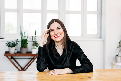 Portrait of a smiling young woman sitting on table