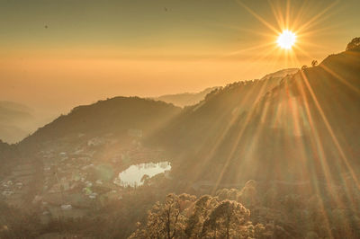 Sunlight streaming on mountain against sky during sunset