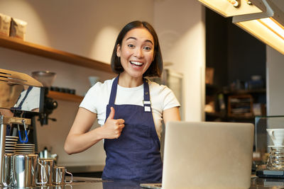 Portrait of young woman using mobile phone while sitting in cafe