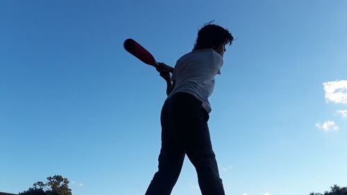 Low angle view of man standing against blue sky