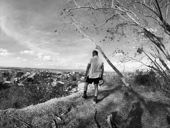 Rear view of woman walking on plants against sky