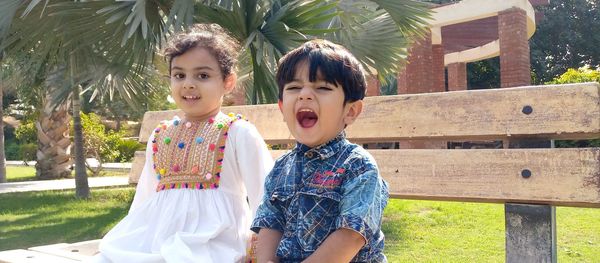 Siblings sitting on bench in park