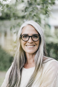 Portrait of smiling woman with long grey hair wearing spectacles