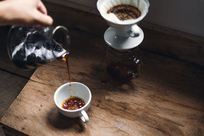 High angle view coffee pouring in cup on table