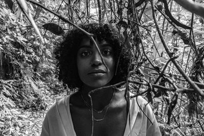 Portrait of young woman by branches in forest