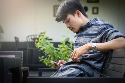Side view of young man sitting on seat