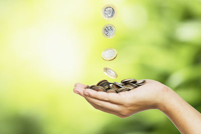 Cropped hand catching coins falling outdoors