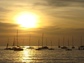 Sailboats sailing on sea against sky during sunset