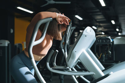 Young tired woman training for cardio equipment at fitness gym