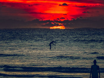 Silhouette man standing on beach against sky during sunset