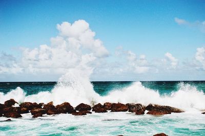 Waves splashing on sea against sky