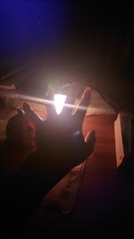 Low angle view of hand holding illuminated light at night