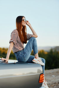 Side view of woman sitting on car