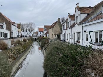 River amidst houses and buildings against sky