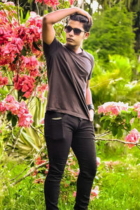 Full length of young man standing against pink flowering plants