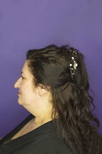 Portrait of woman against purple wall