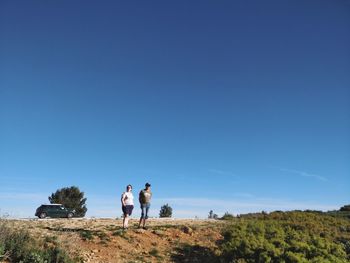 People standing on field against clear blue sky