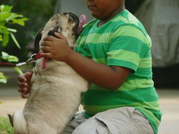 Midsection of boy playing with pug