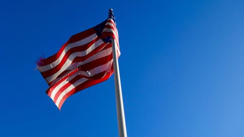 Low angle view of american flag against clear blue sky