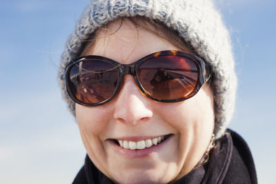 Close-up portrait of smiling woman wearing sunglasses against sky