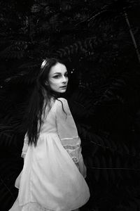 Portrait of beautiful young woman standing against tree