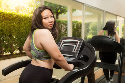 Side view portrait of overweight young woman walking on treadmill in gym