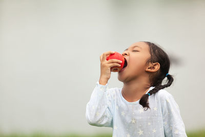 Girl holding ice cream standing against white background