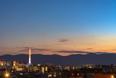 Illuminated buildings in city against sky at sunset