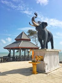 Statue on beach against sky