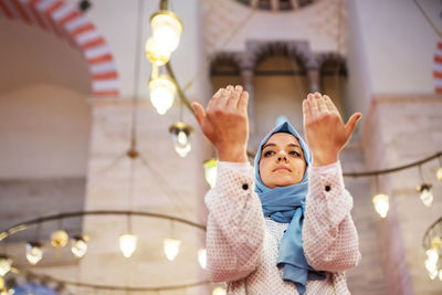 Low angle view of woman praying while sitting in mosque