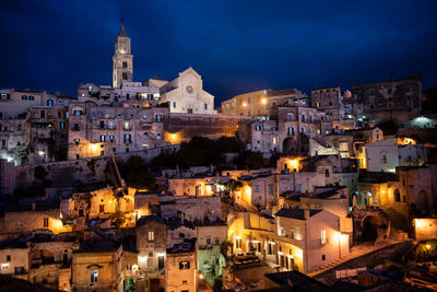 Low angle view of illuminated houses against sky in city at night