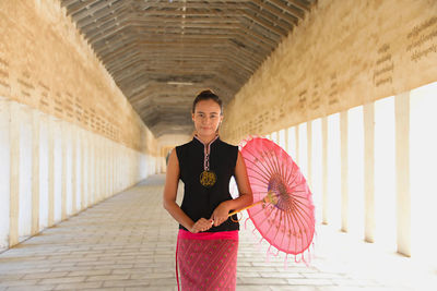 Portrait of smiling young woman standing with umbrella