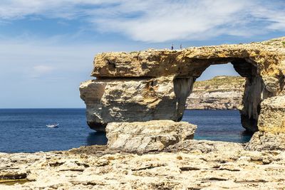 Built structure on rock formation by sea against sky