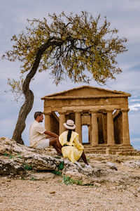 View of buddha sitting by tree against sky