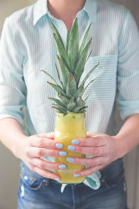 Midsection of woman holding pineapple drink 