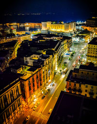 High angle view of illuminated street amidst buildings in city at night