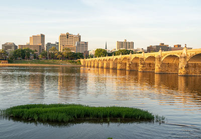 Bridge over river in city against sky