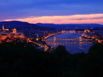 High angle view of illuminated bridge over river in city during sunset