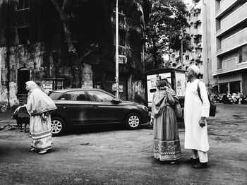 Rear view of people standing on street in city