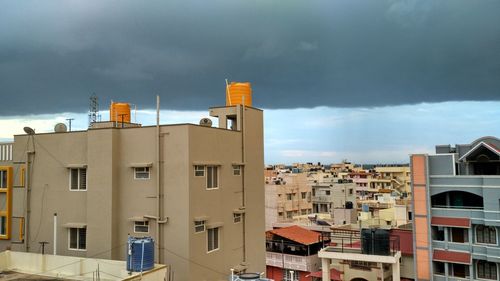 Yellow water tower on building against cloudy sky in city