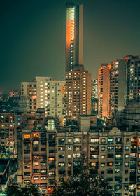 Illuminated buildings in city against clear sky at night