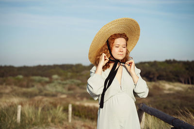 Portrait of young woman wearing hat against sky