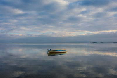 Boat in lake against cloudy sky