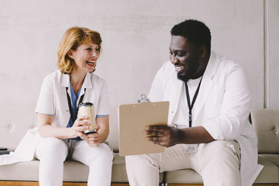 Cheerful male and female doctors sitting on sofa at hospital