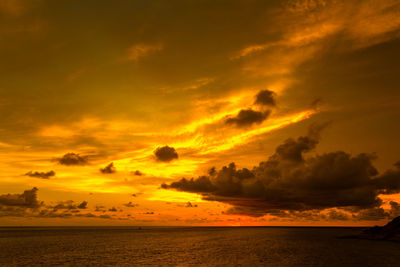 Scenic view of sea against dramatic sky during sunset