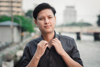 Portrait of young man standing against city