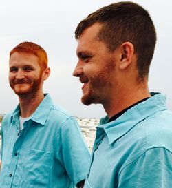 Friends wearing blue shirts standing against sky