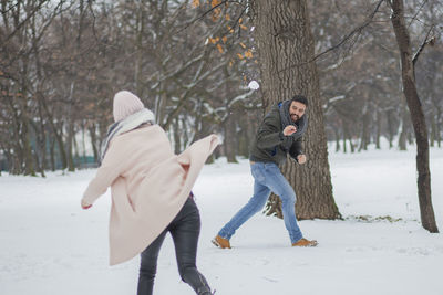 Happy couple playing on snow covered land during winter