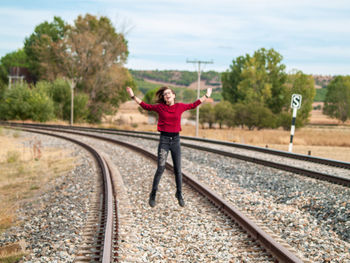Woman standing on railroad track against sky