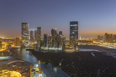 Illuminated buildings in city against sky at night